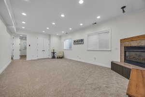 Unfurnished living room with carpet floors, a tile fireplace, ornamental molding, and recessed lighting