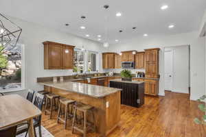 Kitchen featuring dark stone countertops, wood finish cabinetry, a peninsula, and a kitchen island