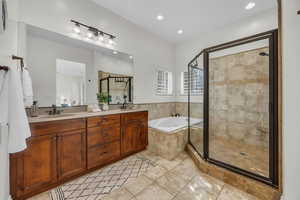 Full bath featuring double vanity, a garden tub, a shower stall, light tile patterned floors, and recessed lighting