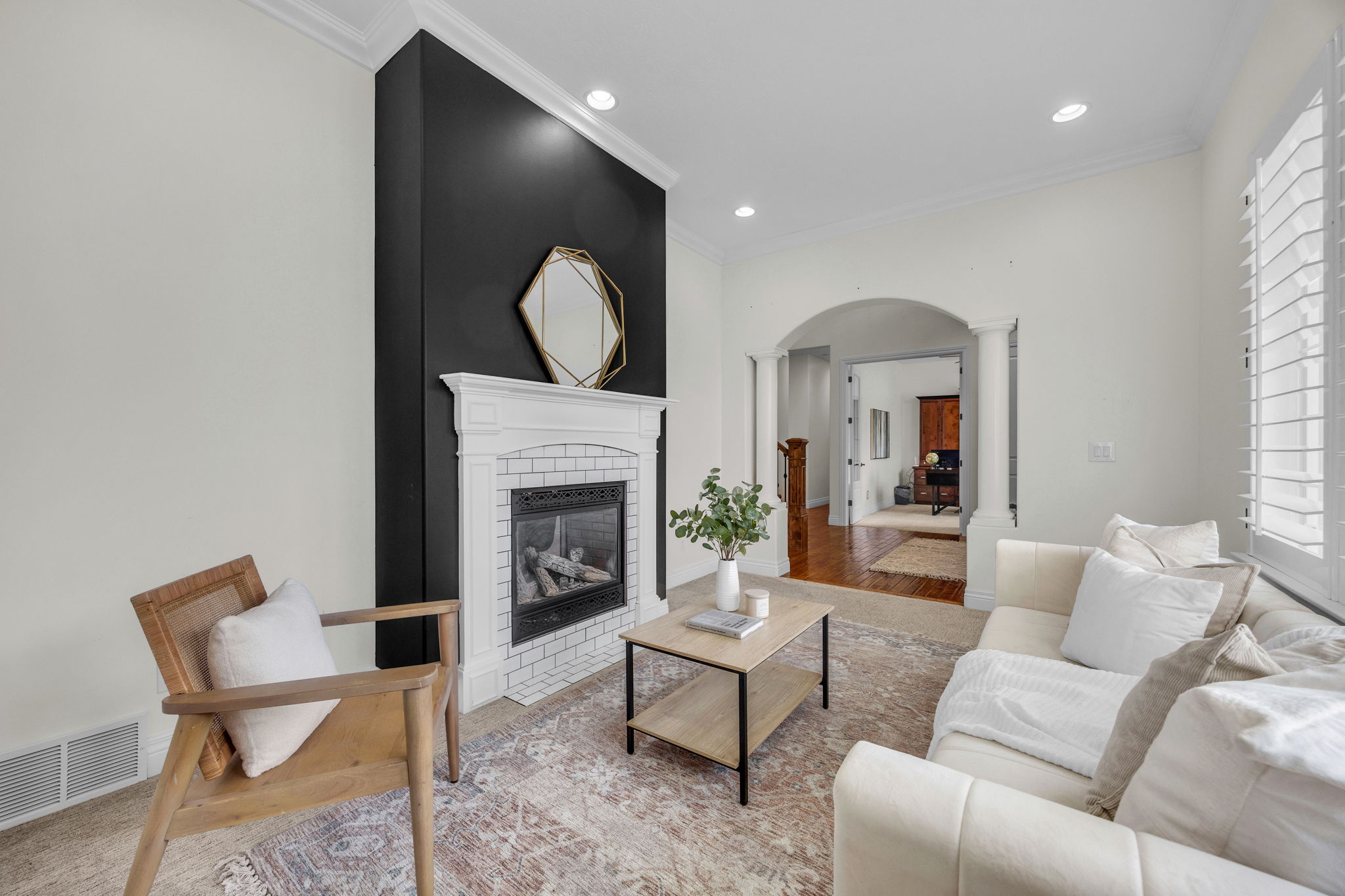 Living room with arched walkways, a brick fireplace, decorative columns, recessed lighting, and crown molding