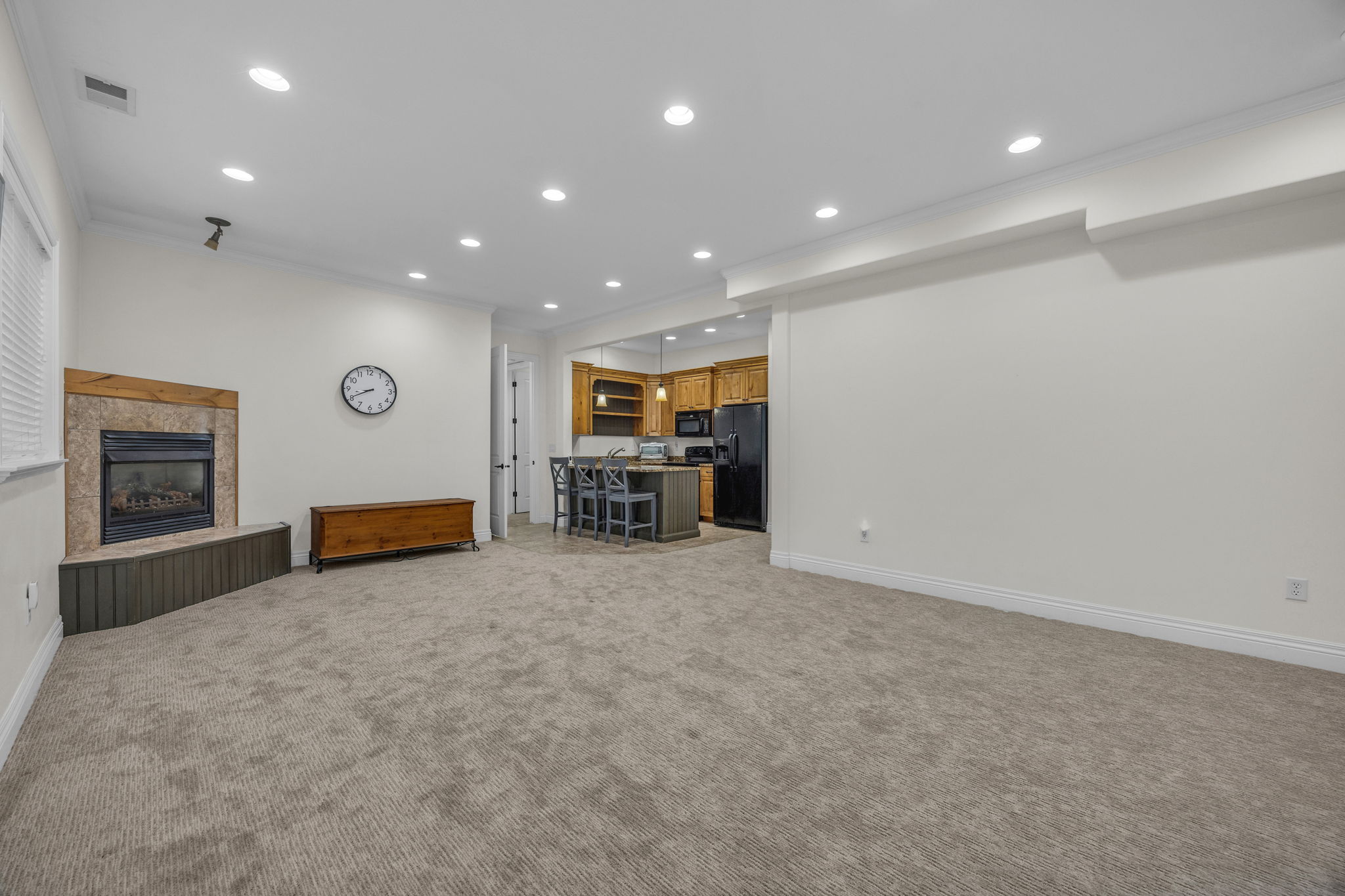 Living area featuring recessed lighting, a fireplace, crown molding, and light carpet