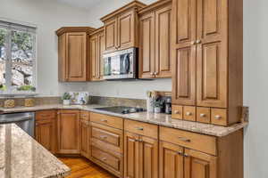 Kitchen featuring wood finish cabinetry, light stone countertops, and stainless steel appliances