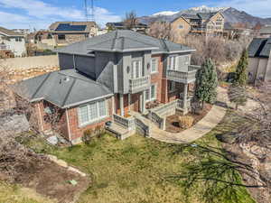 Back of house featuring brick siding, a yard, a residential view, and a balcony