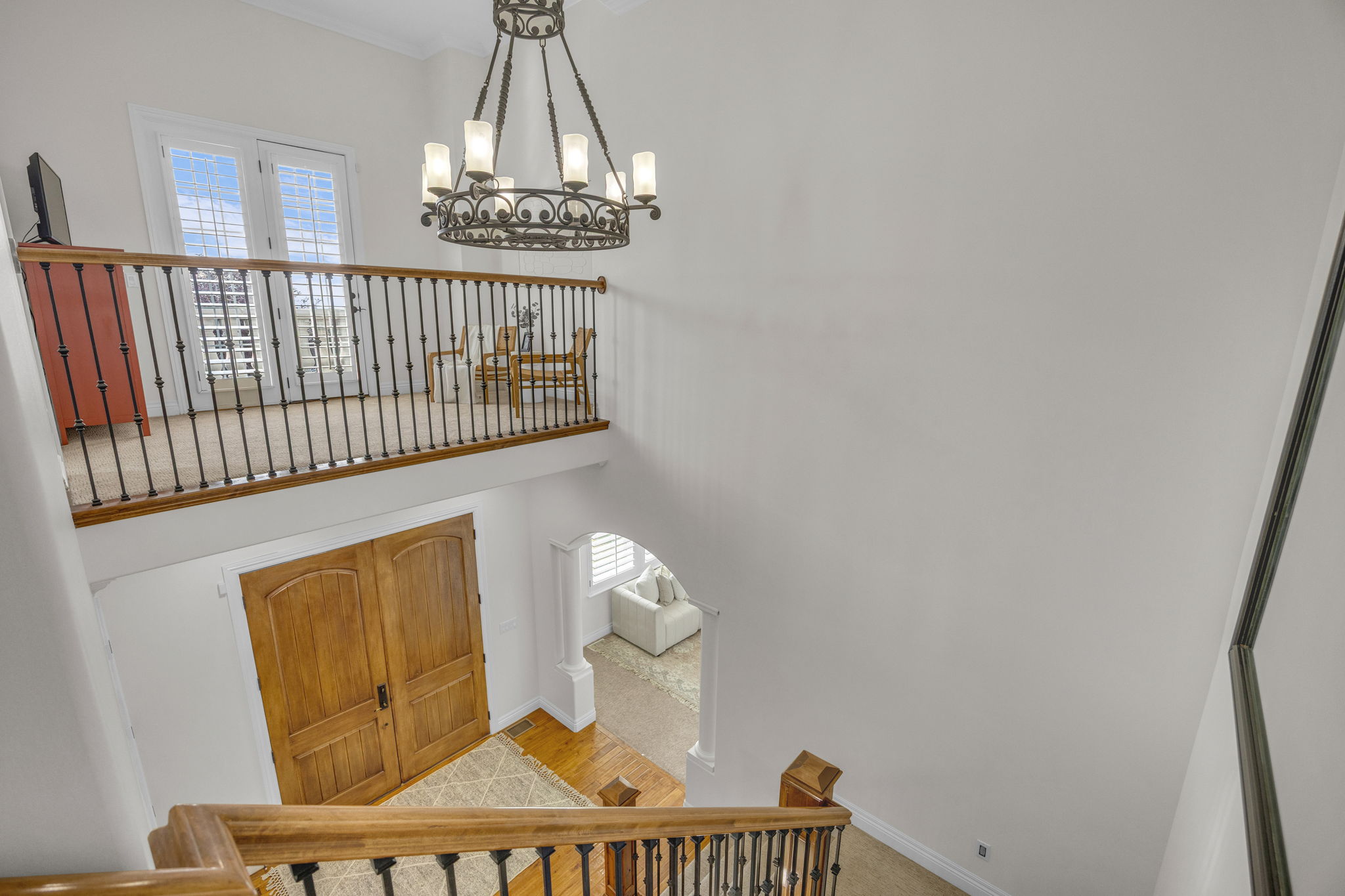 Stairs with hanging lights, arched walkways, a high ceiling, and carpet floors