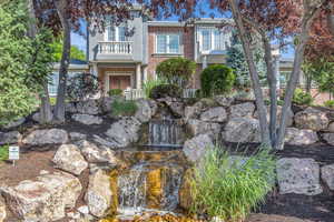 View of front of property featuring a small pond, a balcony, and brick siding