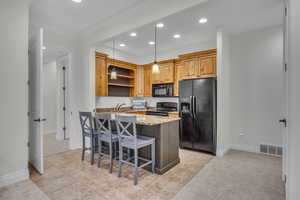Kitchen with light stone countertops, black appliances, a kitchen breakfast bar, open shelves, and a peninsula