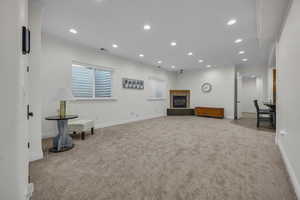 Living room with recessed lighting, a fireplace, light colored carpet, and crown molding