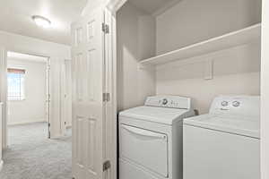 Laundry area with light colored carpet and washing machine and clothes dryer