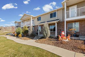 View of front of home with a balcony, brick siding, and a front lawn