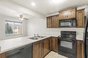 Kitchen with black appliances, light countertops, light tile patterned floors, ceiling fan, and wood finish cabinetry