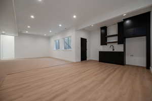 Bar with dark cabinets, recessed lighting, light countertops, light wood-style flooring, and open shelves