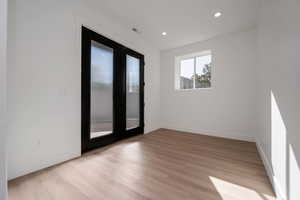 Unfurnished room with french doors, light wood-style floors, and recessed lighting