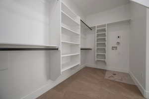 Walk in closet featuring light colored carpet