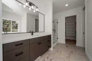 Full bath with vanity, light marble finish flooring, a stall shower, a spacious closet, and recessed lighting