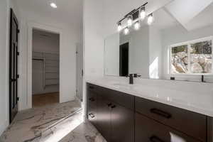 Full bathroom with a spacious closet, vanity, light marble finish flooring, a shower stall, and recessed lighting