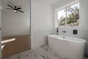 Bathroom featuring a freestanding bath, a ceiling fan, light marble finish flooring, and recessed lighting