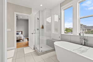 Ensuite bathroom with a stall shower, a soaking tub, light tile patterned flooring, and recessed lighting