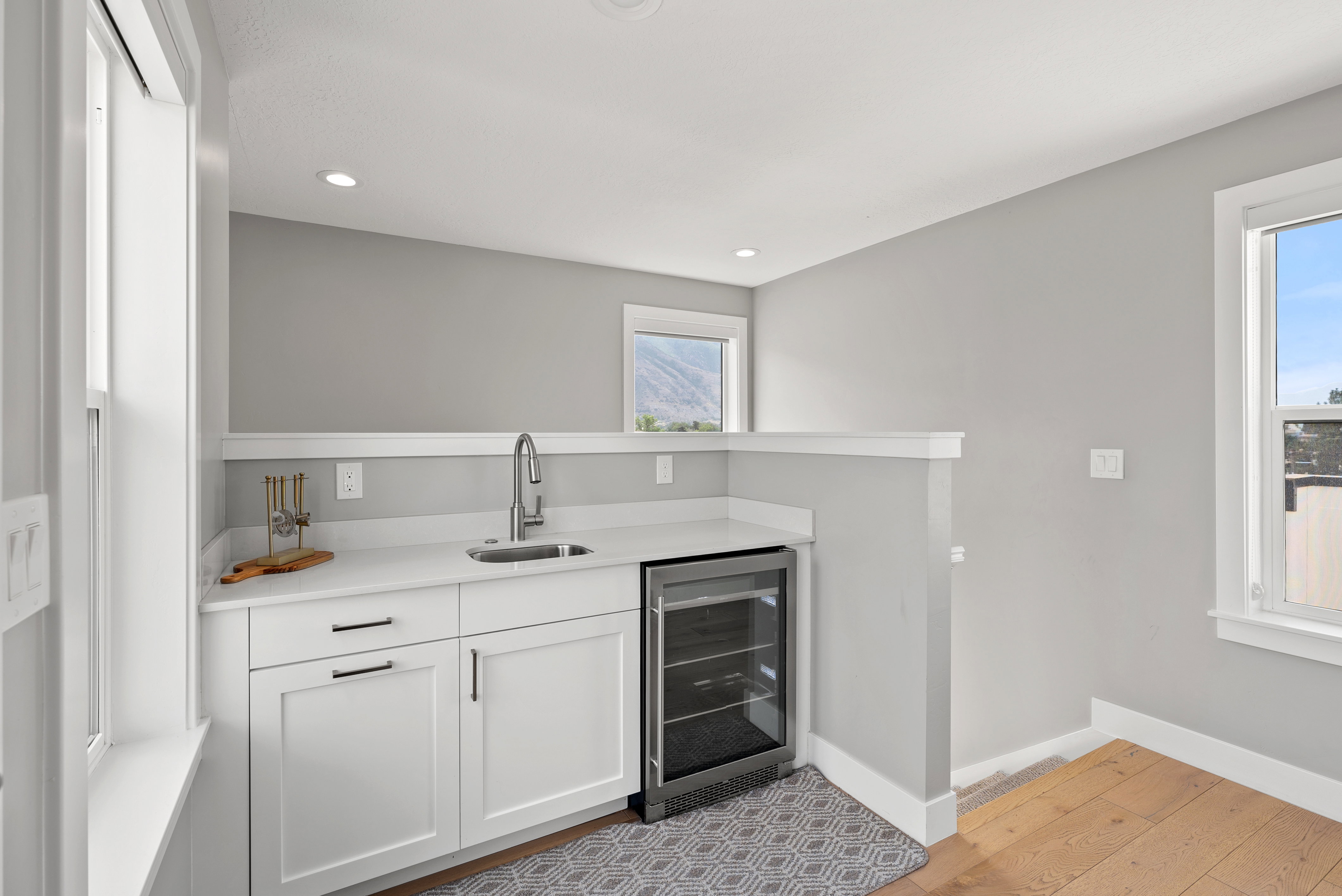 Bar area featuring white cabinetry, wine cooler, light wood-type flooring, recessed lighting, and light stone counters