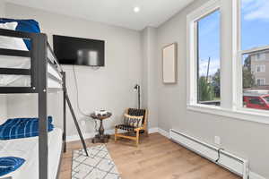 Bedroom featuring a baseboard heating unit, light wood-style floors, and recessed lighting