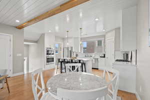 Dining space featuring beamed ceiling, light wood-style floors, and recessed lighting