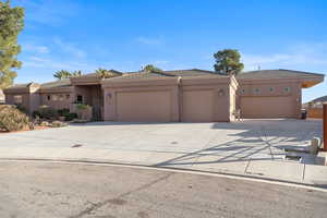 View of front facade with a garage, stucco siding, a tile roof, and driveway
