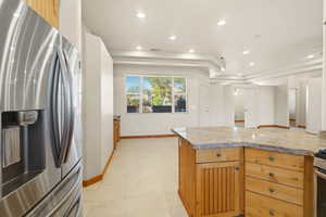 Kitchen with stainless steel fridge, a tray ceiling, recessed lighting, light stone countertops, and open floor plan
