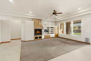 Unfurnished living room featuring a ceiling fan, a tile fireplace, recessed lighting, light colored carpet, and a raised ceiling