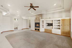 Unfurnished living room featuring a ceiling fan, a tile fireplace, recessed lighting, built in shelves, and a raised ceiling