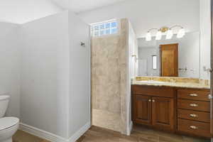 Full bathroom featuring vanity, walk in shower, and wood finish floors