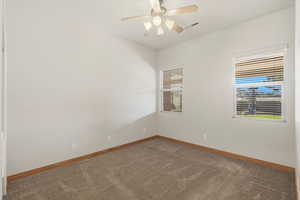 Carpeted empty room with a ceiling fan and baseboards