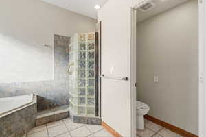 Bathroom featuring a walk in shower, light tile patterned flooring, and a garden tub
