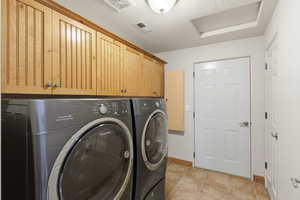 Laundry room with a textured ceiling, independent washer and dryer, cabinet space, and light tile patterned flooring