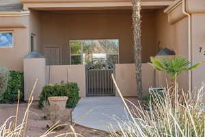 View of exterior entry with a gate, stucco siding, and a patio