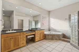 Full bathroom featuring two vanities, a shower stall, a garden tub, light tile patterned floors, and recessed lighting
