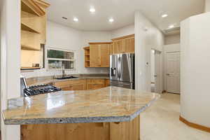 Kitchen with open shelves, a peninsula, light stone counters, stainless steel appliances, and recessed lighting