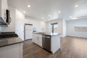 Kitchen featuring stainless steel appliances, dark wood-style flooring, white cabinetry, and recessed lighting