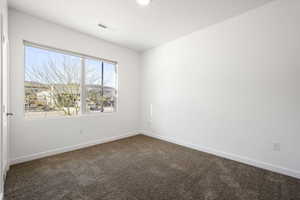 Unfurnished room with baseboards and dark colored carpet