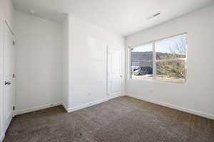 Spare room with dark colored carpet and baseboards