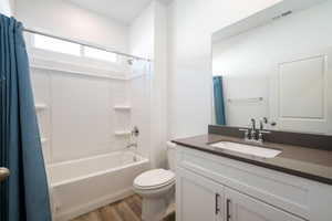 Bathroom featuring vanity, dark wood finished floors, and shower / bathtub combination with curtain