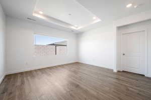 Unfurnished room with light wood-style floors, a raised ceiling, and recessed lighting