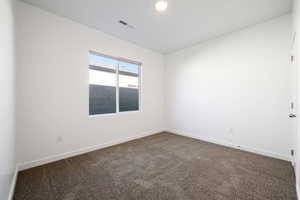 Empty room with dark colored carpet and baseboards