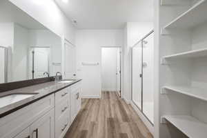 Bathroom with a stall shower, double vanity, and light wood-style flooring