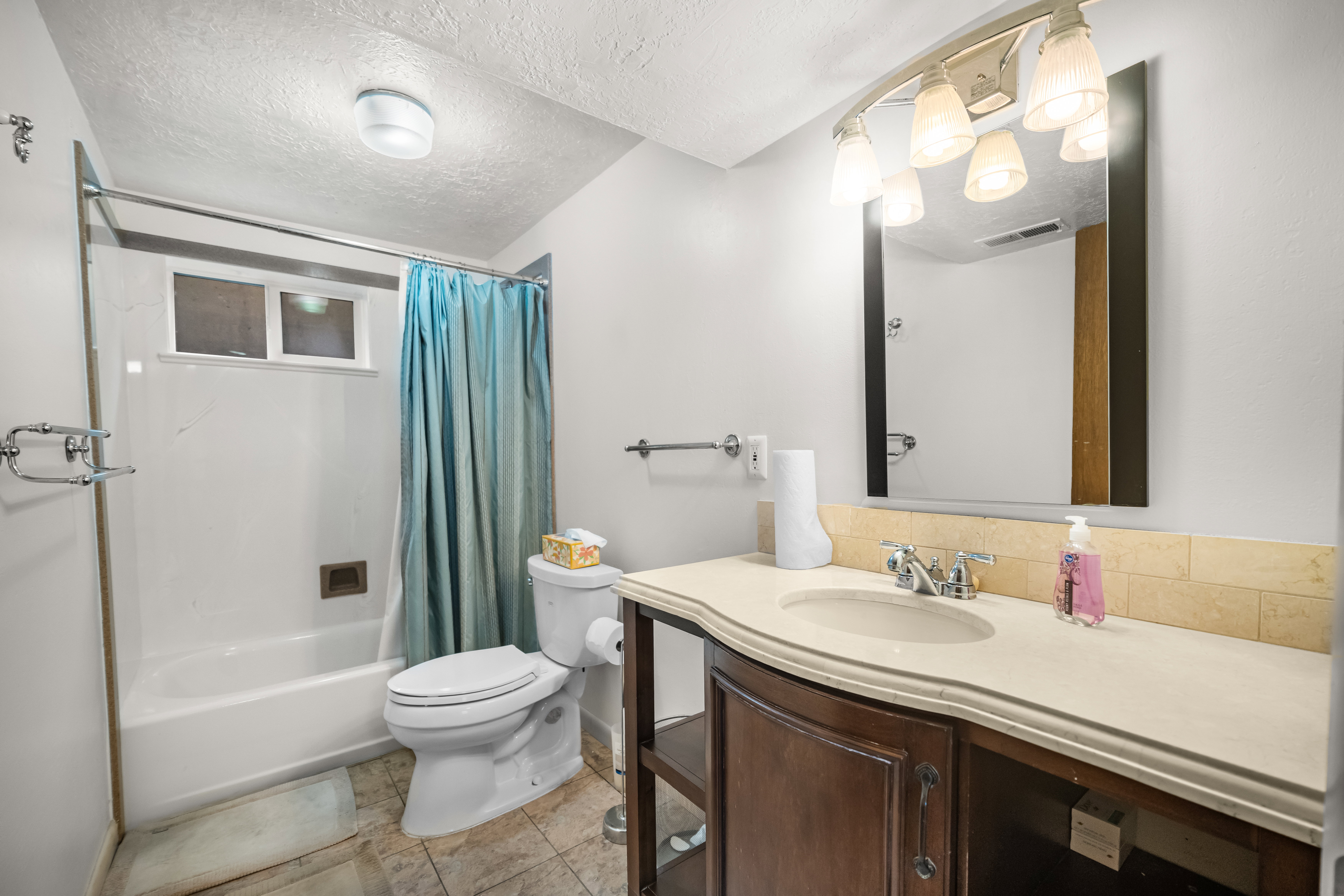 Full bath featuring a textured ceiling, vanity, shower / tub combo, and light tile patterned floors