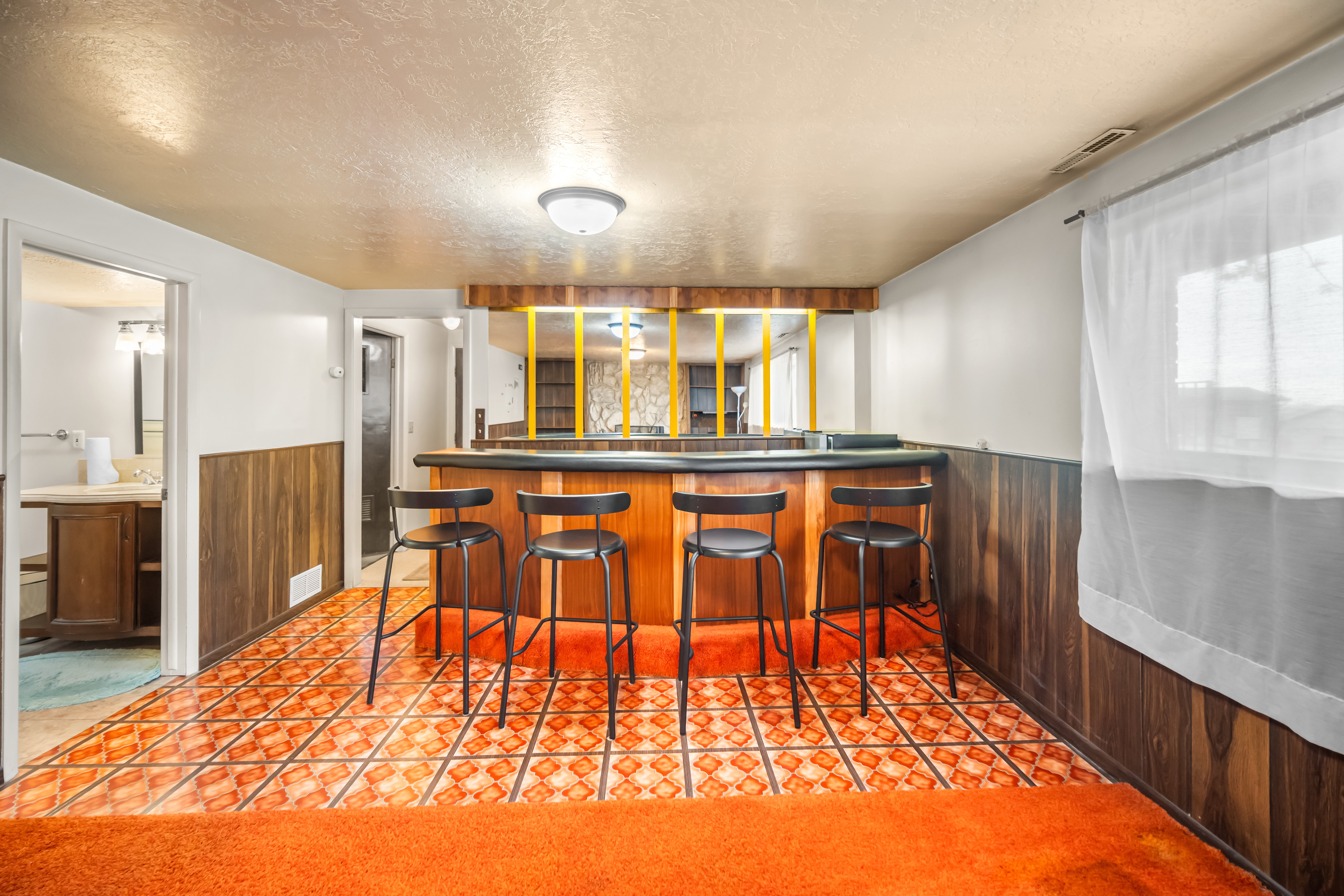 Indoor wet bar with wainscoting, wooden walls, a textured ceiling, dark countertops, and light tile patterned floors