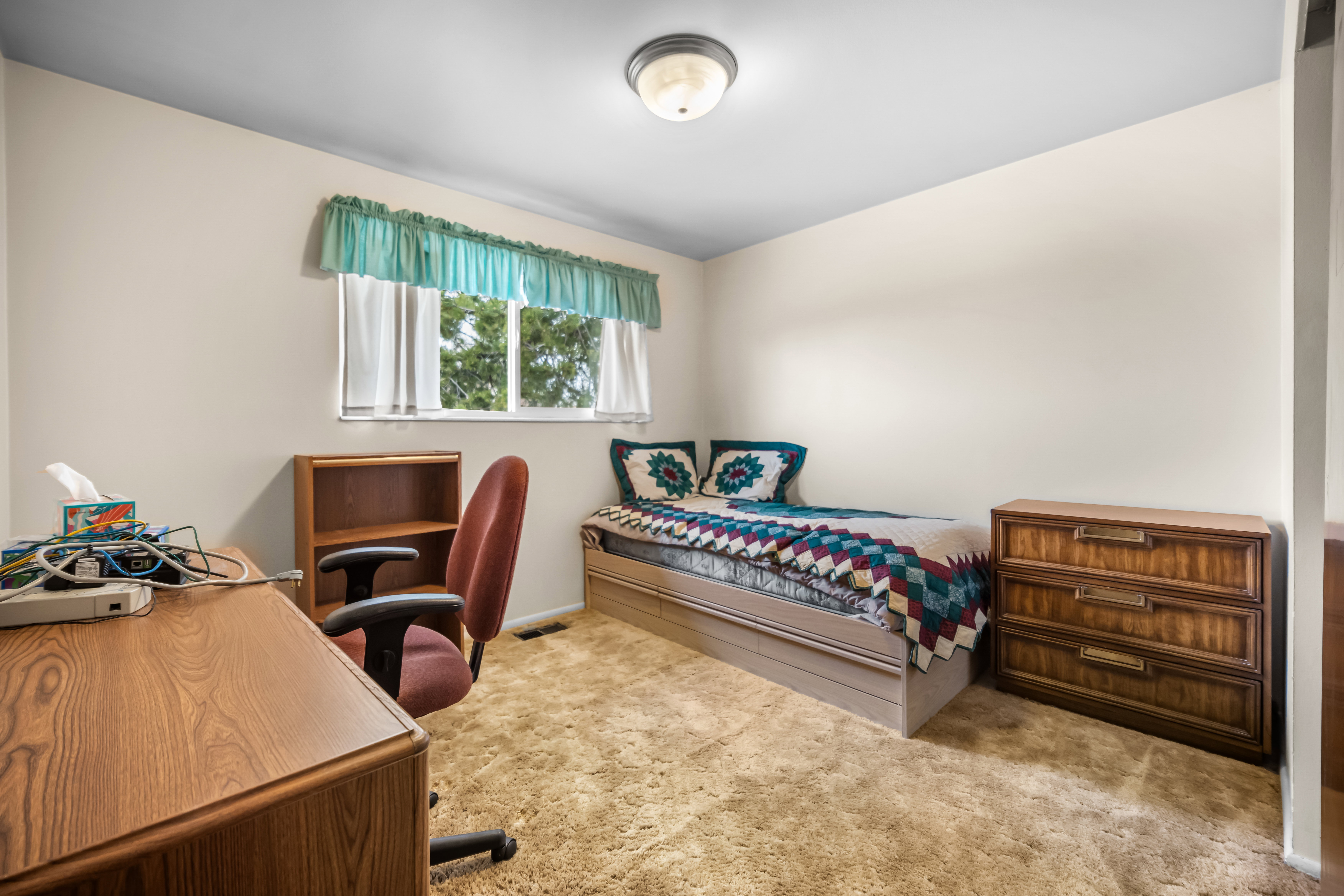 Bedroom with light colored carpet and a desk