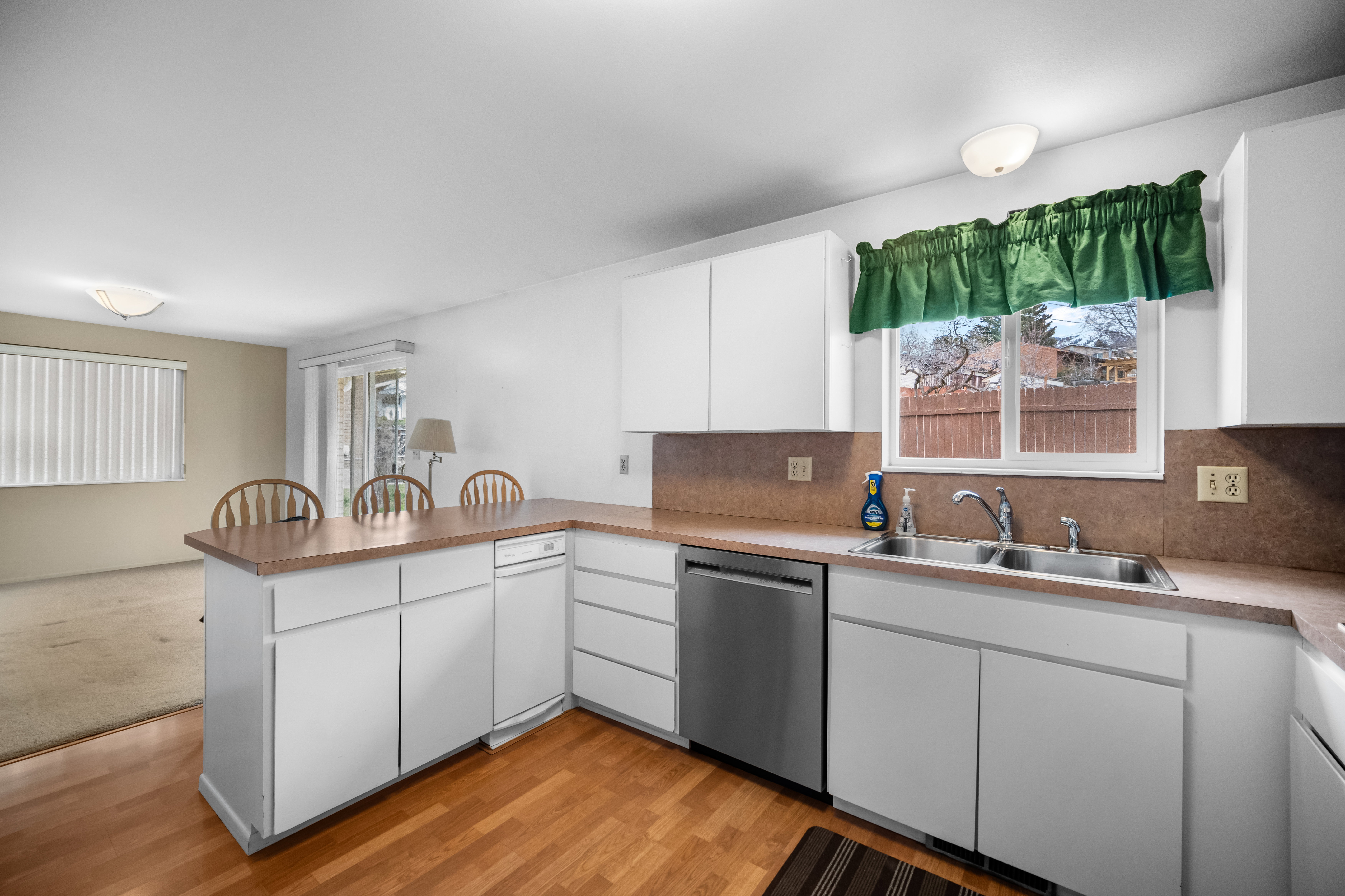 Kitchen with a peninsula, white cabinetry, dishwasher, tasteful backsplash, and light wood-style flooring