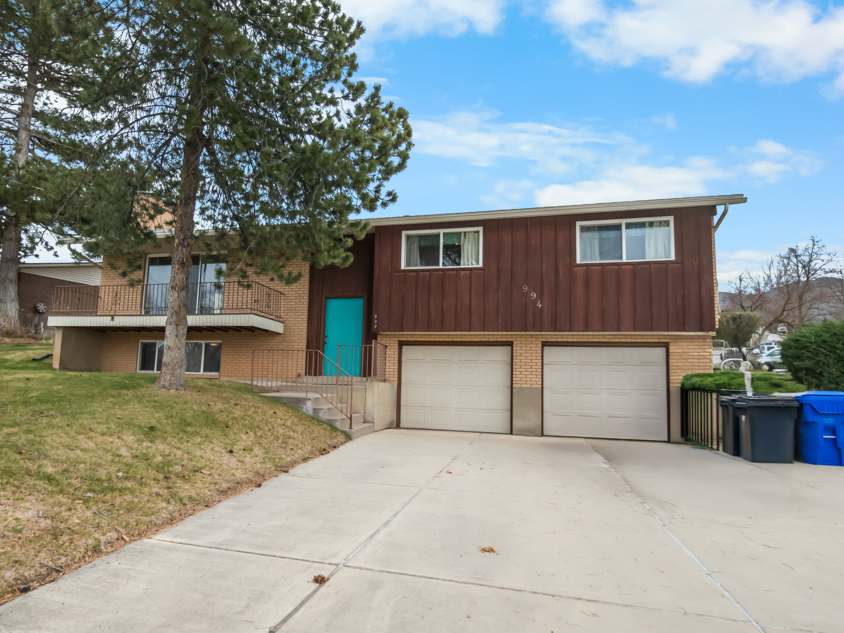 View of front facade with brick siding, driveway, a garage, and a front lawn