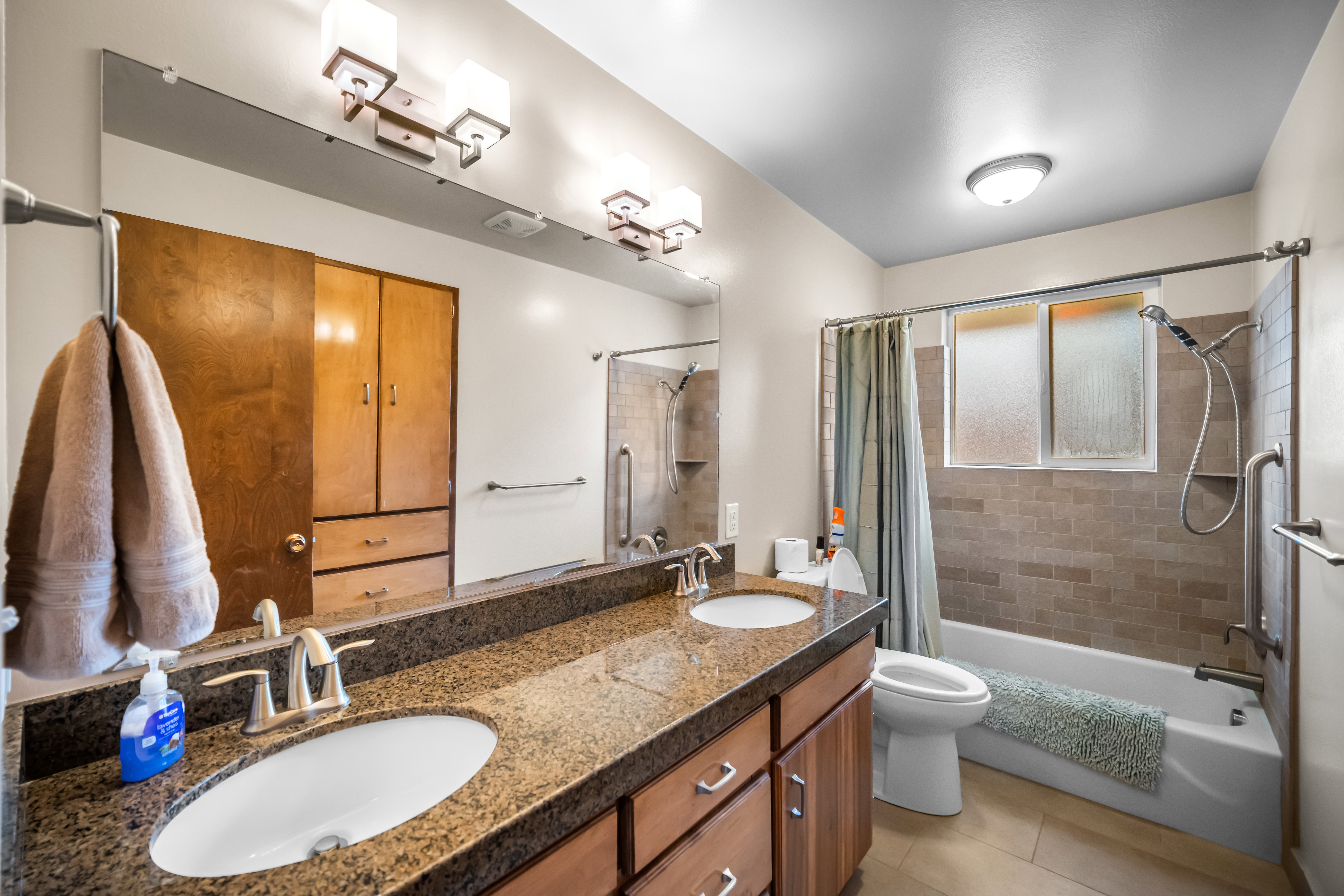 Bathroom featuring double vanity, shower / tub combo, and light tile patterned floors