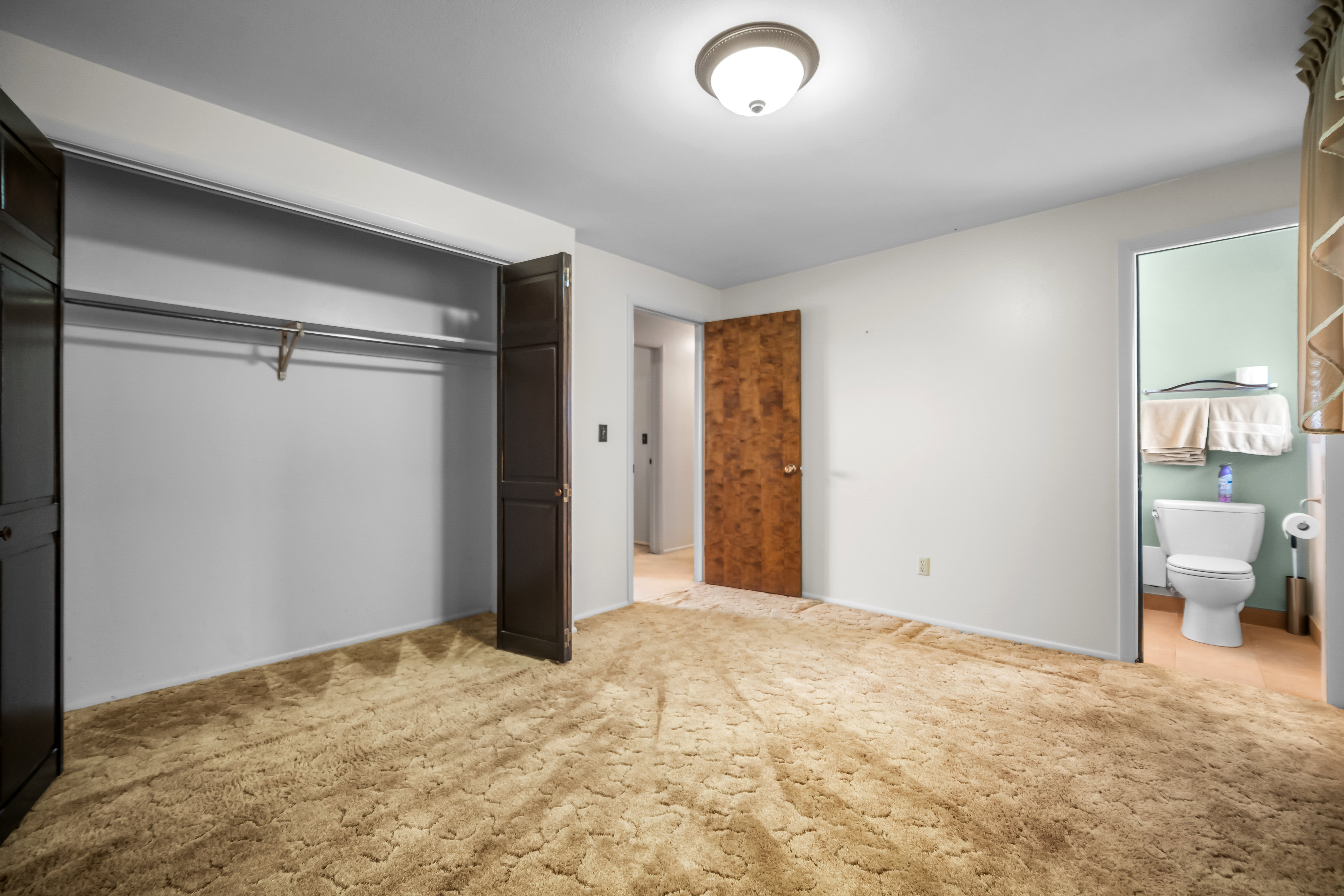 Unfurnished bedroom with light carpet, a closet, and ensuite bath