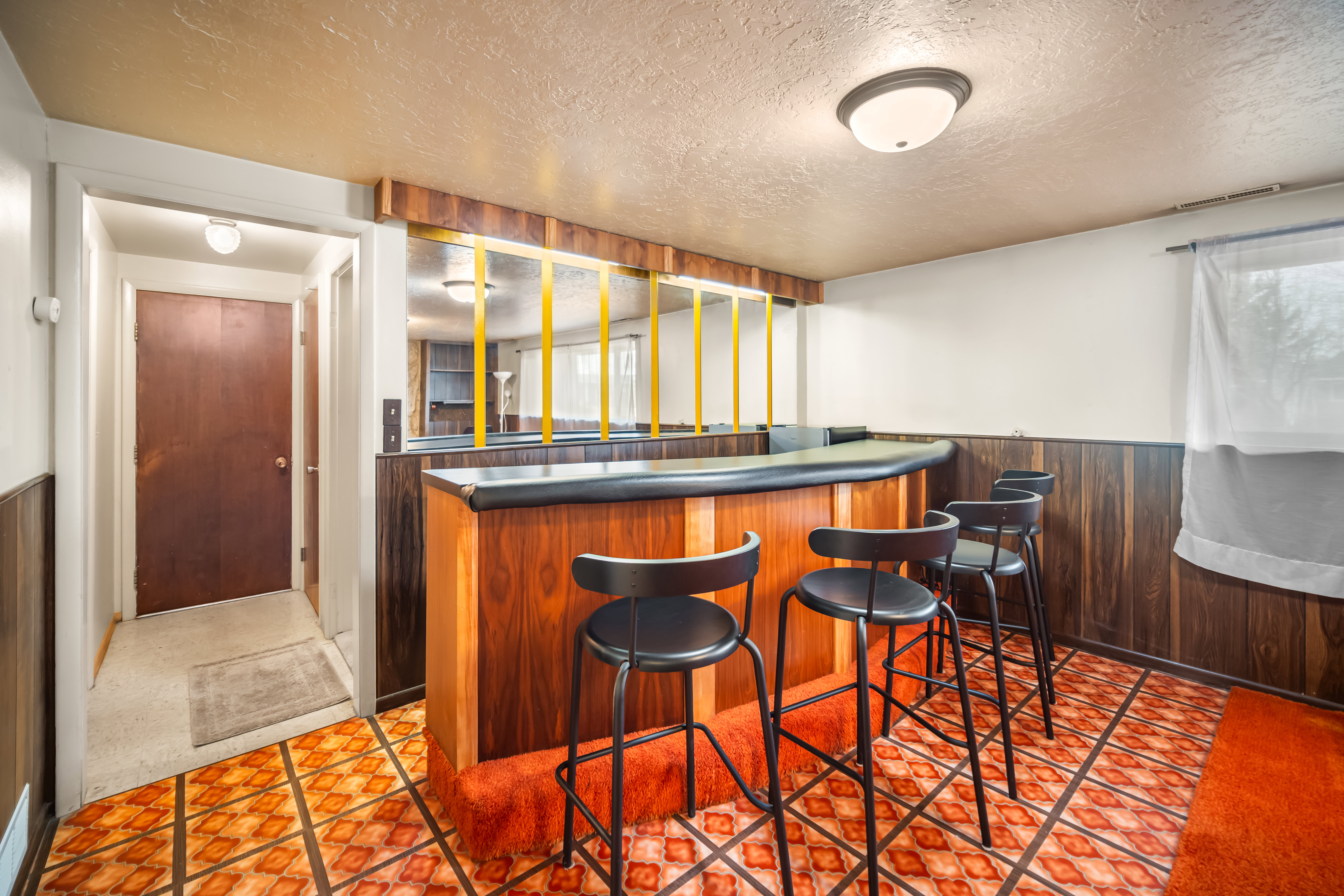 Indoor dry bar featuring a wainscoted wall, a textured ceiling, wood walls, dark countertops, and wood finish cabinetry